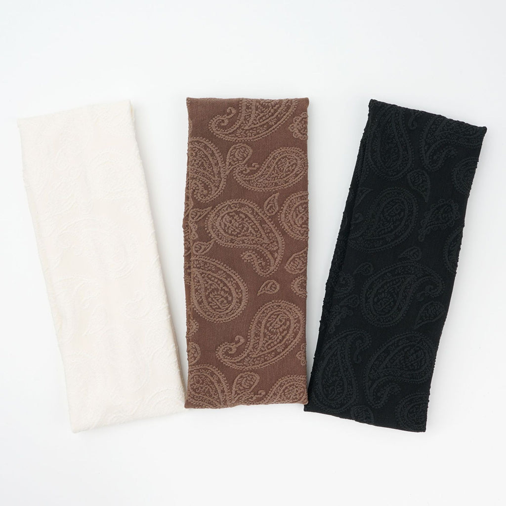 Wide knit headbands with a raised paisley pattern in ivory, coffee, and black