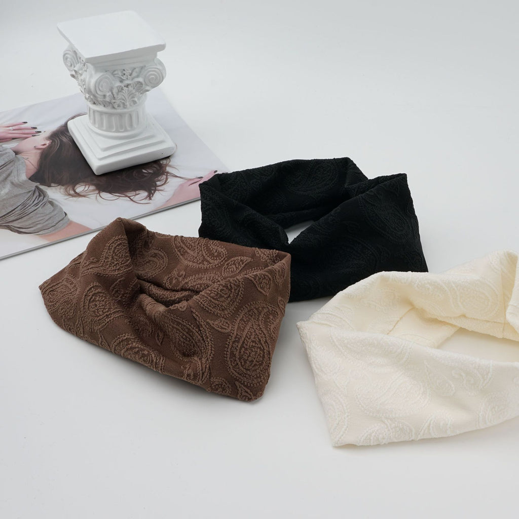 Wide knit headbands with a raised paisley pattern in ivory, coffee, and black