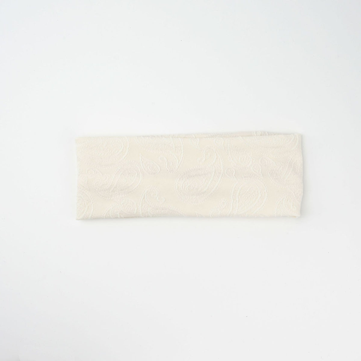 Wide knit headbands with a raised paisley pattern in ivory, coffee, and black