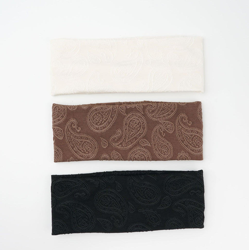 Wide knit headbands with a raised paisley pattern in ivory, coffee, and black